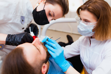 Dental clinic. Professional doctor dentist treats teeth to the patient in the office on modern...