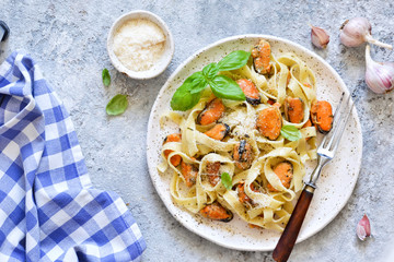 Tagliatella pasta with mussels and cream sauce on the kitchen table. View from above.