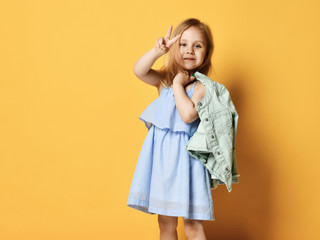 Full length portrait of a cute little child girl in a stylish dress and denim.