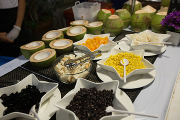 a foodstand saling coconut, corn, mango bread and black beens, Thailand