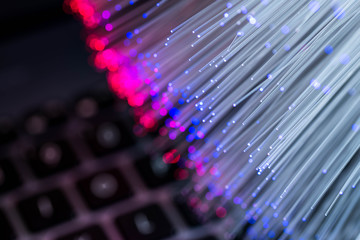 Glowing colorful optical fibres over laptop computer keyboard , image for background.