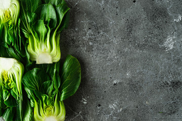 Baby bok choi halves on gray background. Top view with copy space. Horizontal image