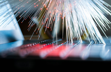 Glowing colorful optical fibres over laptop computer keyboard , image for background.