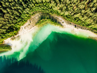 Aerial top down view of beautiful green waters of lake Gela. Birds eye view of scenic emerald lake surrounded by pine forests.