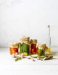 Vegetable preserves in glass jars, cooking ingredients on white background. Vertical image with copy space