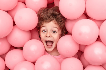 Excited boy lying in balloons - obrazy, fototapety, plakaty