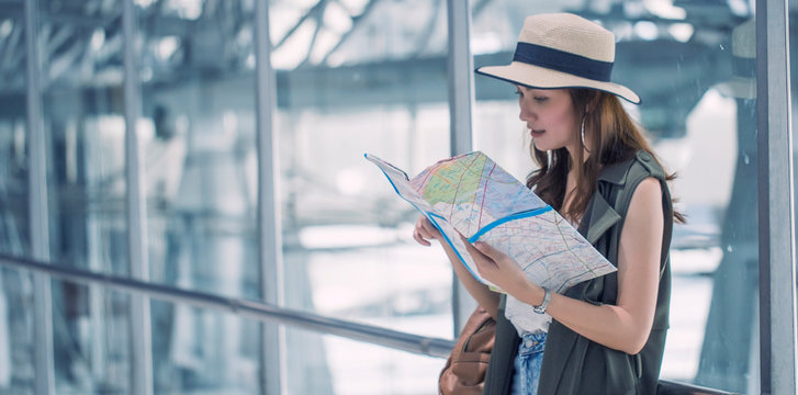 Asian women, beautiful standing read map and search destinations plan to solo traveler at terminal in airport. Vacation and travel concept