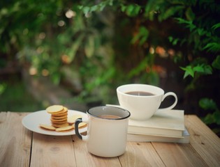 a cup of hot coffee  on a old wooden table.  garden background.