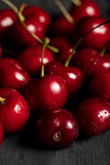 close up view of red delicious and ripe cherries with water drops on wooden table