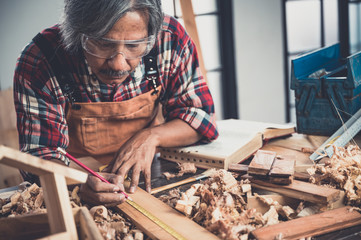 Woodwork and furniture making concept. Carpenter in the workshop marks out the details of the...