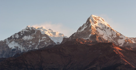 Poonhill view of Annapurnas. Warm pink and orange sunrise light over Annapurna mountain range with blue sky and beautiful clouds, view from Poon hill in Himalayas, Nepal. Annapurna one and Annapurna s - obrazy, fototapety, plakaty
