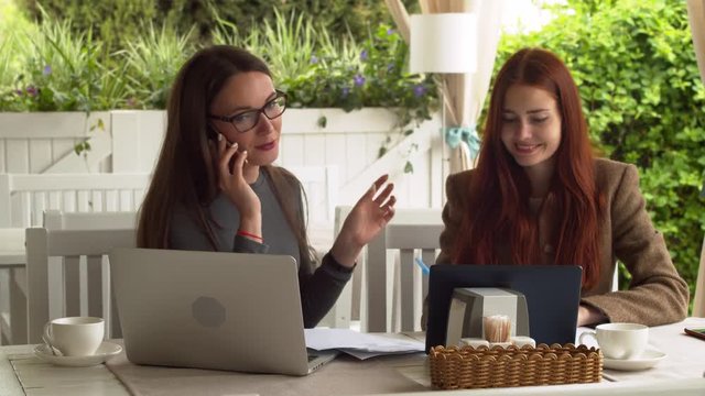 Brunette in big glasses talks on her phone discussing new interview for a lob at the cafe slow motion