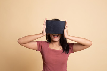 Young Asian woman with a computer tablet over her face.