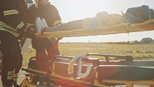 On the Car Crash Traffic Accident Scene: Paramedics and Firefighters Rescue Injured Victim Trapped in the Vehicle. Extricate Person Using Stretchers, Give First Aid and Transport Them to Hospital