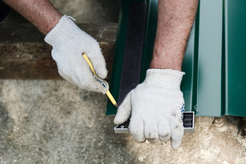  the master draws on metal with a simple pencil on a ruler, the master measures the cut line on the patterns, the process of cutting a metal sheet