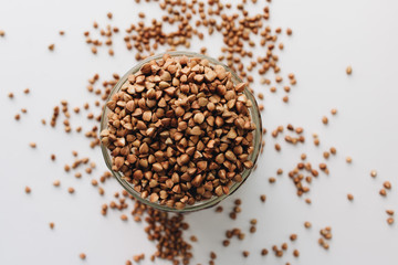 Raw buckwheat in glass on white background