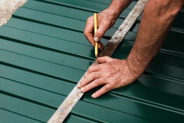  the master draws on metal with a simple pencil on a ruler, the master measures the cut line on the patterns, the process of cutting a metal sheet
