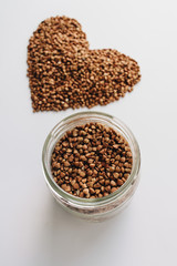 Raw buckwheat on white background shaped as heart symbol