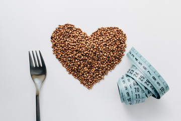 Raw buckwheat on white background shaped as heart symbol