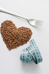 Raw buckwheat on white background shaped as heart symbol