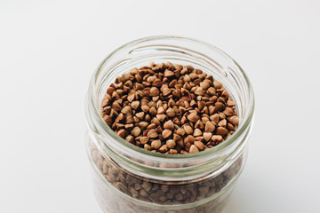 Raw buckwheat in glass on white background