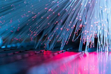 Glowing optical fibres, laptop computer keyboard, abstract technology background image.