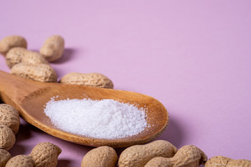 Peanuts and wooden spatula with salt minimal on purple background backdrop food nut texture copy space angle view