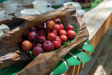 This is Thailand red plum. it is sour and astringent. it is in the art wood basket on the wood counter.