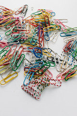 Pile of colorful paper clips on white background, flat lay