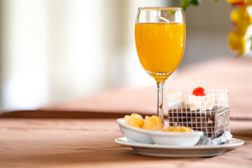 Orange juice in champagne glass with cake and bagery beside.