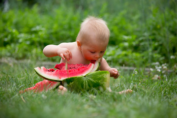  Cute toddler child, baby boy, eating ripe watermelon in garden