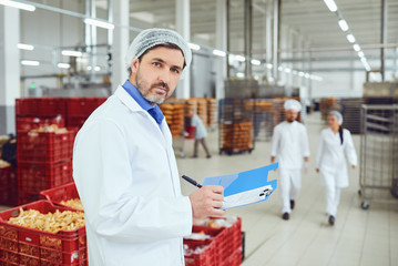 Technologist inspector makes an entry in the folder with the papers at the factory