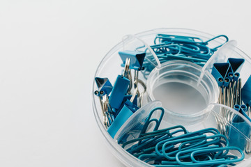 Pile of blue paper clips in organiser on blue background