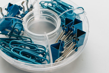 Pile of blue paper clips in organiser on blue background