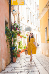 Obraz na płótnie Canvas tourist woman in yellow sundress walking by small croatian city street