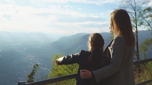 Woman and her daughter enjoying sunrise from top of mountain.