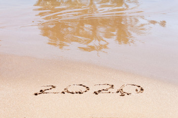 Happy new year 2020 text on the beach. Planning vacation.