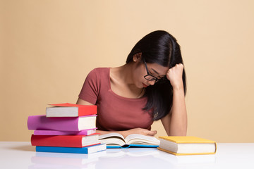 Exhausted Young Asian woman read a book with books on table.