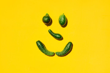 Different sizes and forms cucumbers on a yellow background forms a smiling face. Smile, face,...