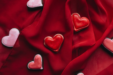 Fototapeta premium Cookies in heart shape with red glaze on red textile