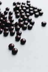Pile of scattered chocolate dragee on white background