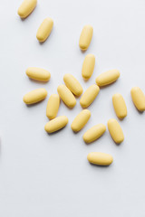 Scatterded yellow pills on white background 