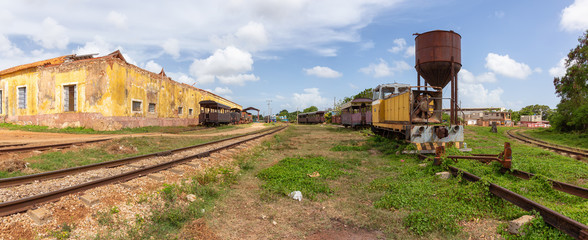 View of an Abandonned rail road station with an old train during a sunny and cloudy day. Taken in Trinidad, Cuba.