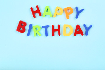 Text Happy Birthday by plastic letters on blue background