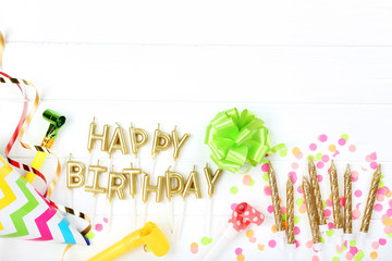 Happy Birthday candles with party decorations on white wooden table
