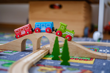 Fototapeta premium baby hands playing with wooden train set on wooden rails on a carpet in nursery