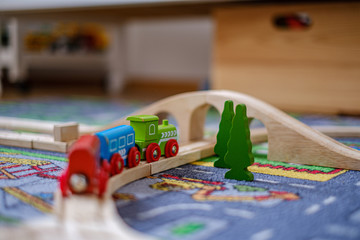 Fototapeta premium baby hands playing with wooden train set on wooden rails on a carpet in nursery