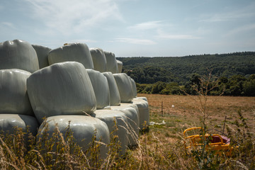 Heuballen eingepackt in weisse Plastikfolie gestapelt auf einem Feld