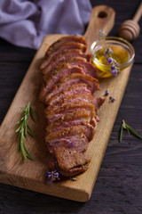 Sliced duck breast, lavender honey and rosemary on serving board