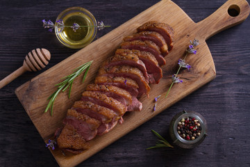 Sliced duck breast, lavender honey and rosemary on serving board
